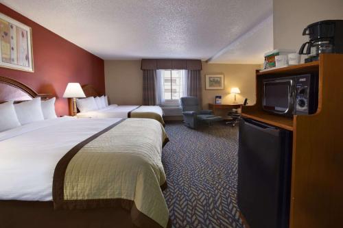 オクラホマシティにあるBaymont by Wyndham Oklahoma City Airportのベッド2台、薄型テレビが備わるホテルルームです。