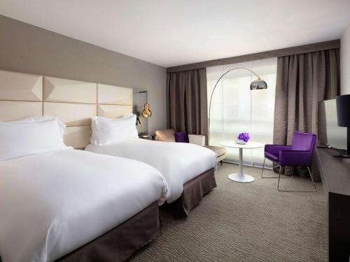 a hotel room with two beds and a table at Sofitel Warsaw Victoria in Warsaw