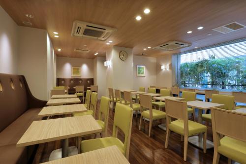 東京的住宿－Keio Presso Inn Gotanda，餐厅设有木桌和黄色椅子