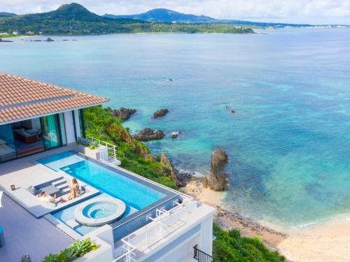 a house with a swimming pool next to the ocean at Halekulani Okinawa in Onna