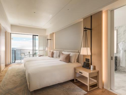 a bedroom with a large bed and a balcony at Halekulani Okinawa in Onna