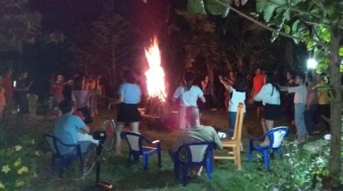 grupa ludzi stojących wokół ognia w nocy w obiekcie Sunny Field Eco Stilt House w mieście Cat Tien