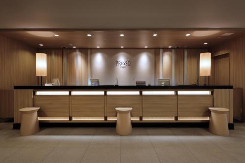 a lobby with a counter with two stools in front at Keio Presso Inn Gotanda in Tokyo