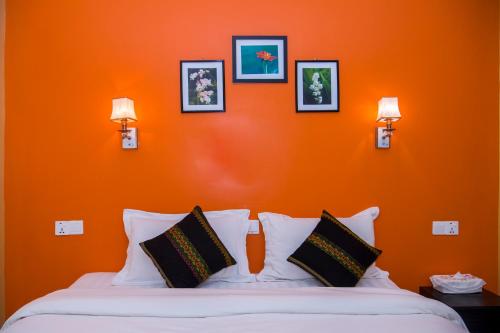 a bedroom with an orange wall and a bed with pillows at The Villager lodge in Ngapali