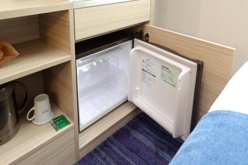 a small refrigerator in a cabinet in a room at Keio Presso Inn Gotanda in Tokyo