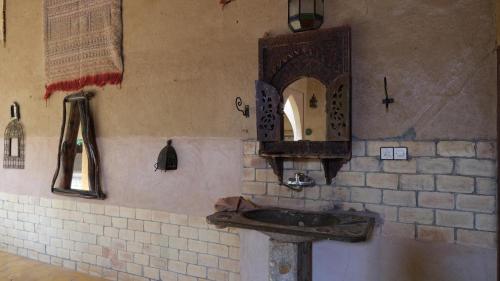 uma casa de banho com um lavatório e um espelho na parede em Maison Merzouga Guest House em Merzouga