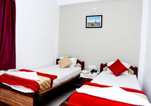 ブッダガヤにあるSatiya Guest Houseの赤と白のシーツが備わる客室のベッド2台