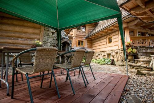 a table and chairs under a green umbrella on a deck at Ośrodek Wypoczynkowy Marymont przy Dolinie Kościeliskiej in Kościelisko