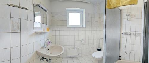 a white bathroom with a sink and a toilet at hotel das deichhaus in Gorleben