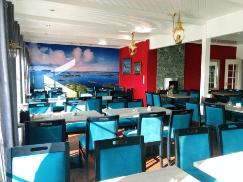 a dining room with tables and blue chairs at Røst Bryggehotell in Røst
