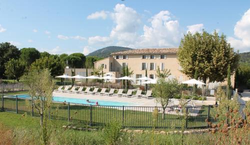 ein Resort mit einem Pool und Stühlen sowie einem Gebäude in der Unterkunft Clos des Oliviers Grimaud - Meublé de Tourisme in Grimaud