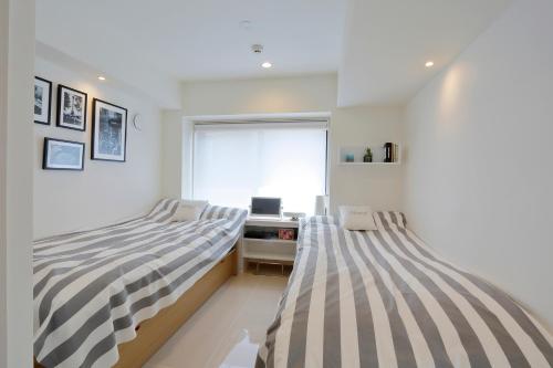 two beds in a bedroom with a desk and a window at La Krasse Sumida in Tokyo