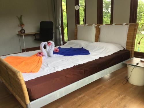 uma cama com dois cisnes sentados em cima dela em Vacation House with tropical garden and private pool em Rayong