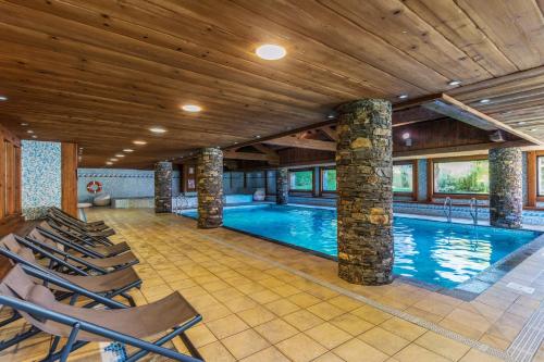 - une piscine dans une pièce avec des chaises dans l'établissement Résidence Pierre & Vacances Premium Les Fermes Du Soleil, aux Carroz d'Arâches