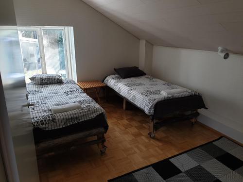 two beds in a small room with a window at Talvitaival Apartments in Varkaus