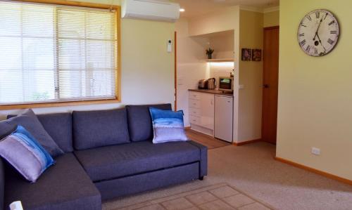 sala de estar con sofá azul y reloj en Maydena Mountain Cabins en Maydena