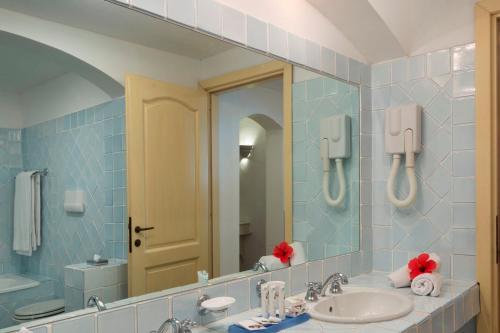 a bathroom with a sink and a mirror at Hotel La Bisaccia in Baja Sardinia