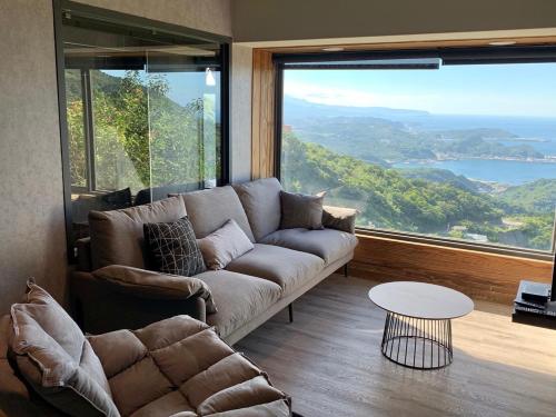 a living room with a couch and a large window at Something Easy Inn in Jiufen