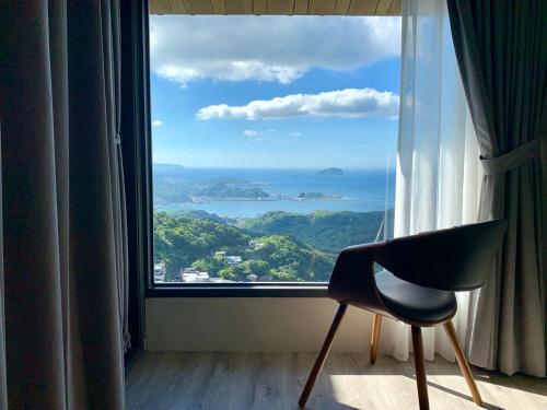 a chair sitting in front of a large window at Something Easy Inn in Jiufen