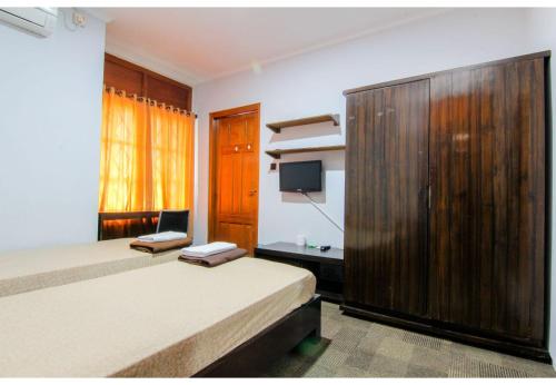 a bedroom with a bed and a large wooden cabinet at Embe Enem Homestay in Yogyakarta