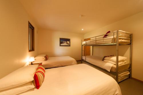 two beds in a room with two bunk beds at Bears Den Mountain Lodge in Hakuba