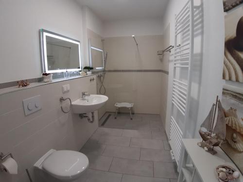 La salle de bains blanche est pourvue de toilettes et d'un lavabo. dans l'établissement Ferienwohnung SteinReich, à Glowe