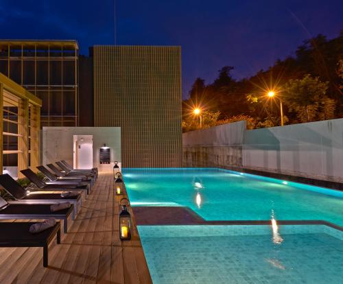 a swimming pool with lounge chairs on a building at night at Has Pattaya in Pattaya South