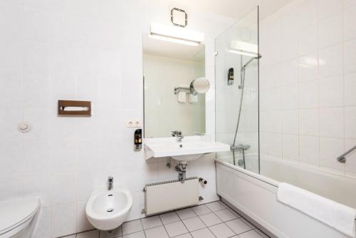 a white bathroom with a sink and a toilet at ARVENA Kongress Hotel - Hotel in der Wagnerstadt in Bayreuth