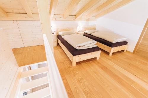 twee bedden in een kamer met houten vloeren bij Baumgartnerhof MÜLLER THURGAU in Cortaccia