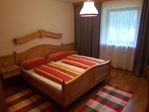 1 dormitorio con cama de madera y 2 almohadas rojas en Feldlechn, en Lappago