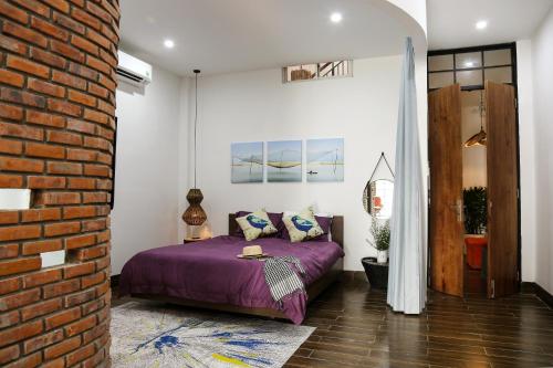 um quarto com uma cama roxa e uma parede de tijolos em Chaca House em Da Nang