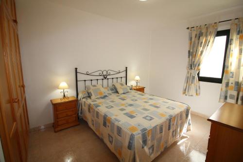 1 dormitorio con 1 cama, 2 mesitas de noche y ventana en Cala Apartamentos, en Giniginámar