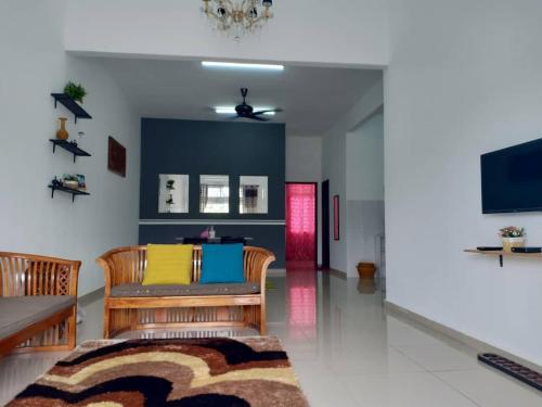 愛極樂的住宿－Ana Homestay Ayer Keroh Melaka，客厅配有两把椅子和电视