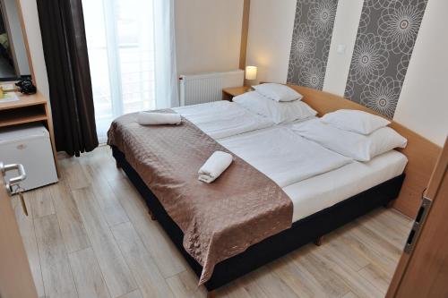 a bedroom with a large bed with white sheets and pillows at Hotel Papillon in Budapest