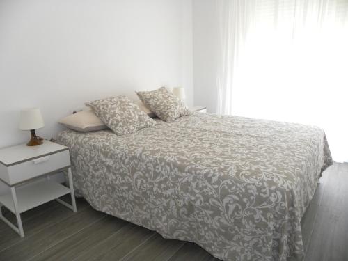 um quarto branco com uma cama, uma mesa de cabeceira e uma janela em El paradis em Lloret de Mar