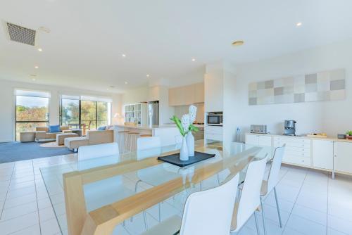 a kitchen and living room with a dining table and chairs at 3 Bedroom Townhouse - Pool and Tennis Court Access in Torquay