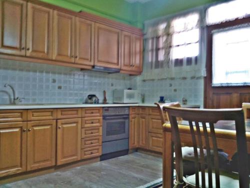 a kitchen with wooden cabinets and a chair in it at Detached House 120 sq.m., Kalamia Beach. in Korinthos
