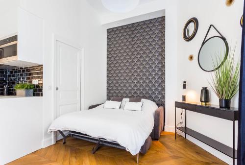 een witte slaapkamer met een bed en een spiegel bij CMG Trocadéro / Doumer in Parijs