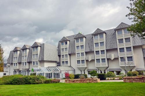 a row of apartment buildings with a green lawn at H+ Hotel Wiesbaden Niedernhausen in Niedernhausen