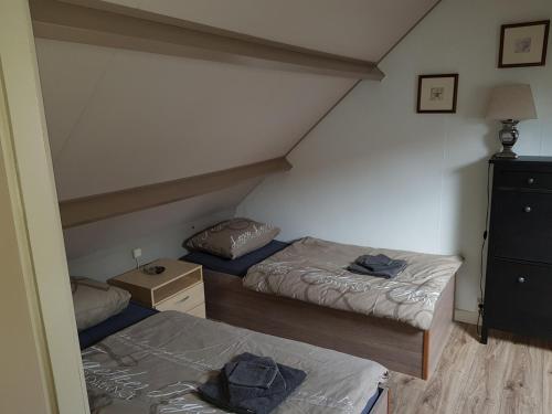 Cette chambre mansardée comprend 2 lits et une commode. dans l'établissement Brugman, à Egmond aan Zee