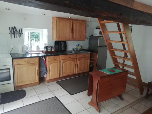une cuisine avec des placards en bois et une échelle dans l'établissement La Petite Maison, à Beauchêne