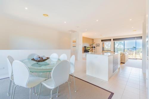 a kitchen and dining room with a glass table and white chairs at Stylish 3 Bedroom Townhouse - Free Parking in Torquay