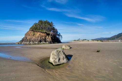 a rock in the sand on a beach at Sittin' By The Sea in Pacific City