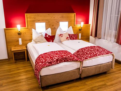 2 camas en una habitación de hotel con paredes rojas en Landhotel Timmerer en Möderbrugg