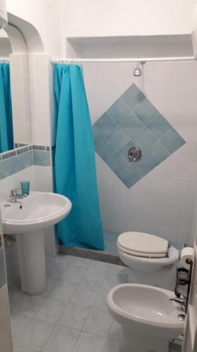 a bathroom with a toilet and a blue shower curtain at Sweet Home in Ischia