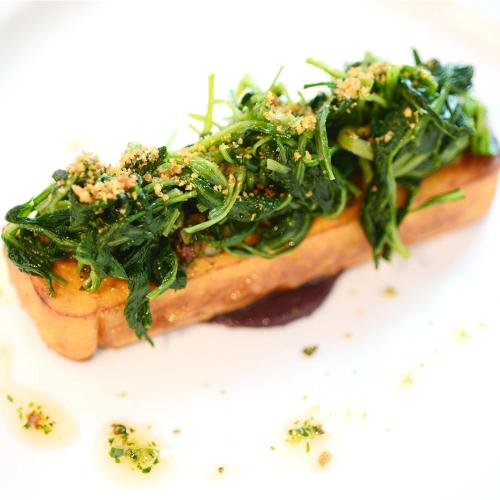 a piece of food with greens on top on a white plate at Hotel Repubblica 55 in Biella