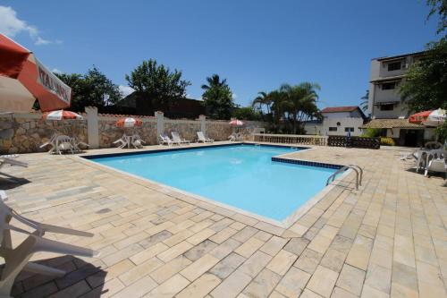 a large swimming pool with chairs and a fence at Leviv Praia Hotel in Caraguatatuba