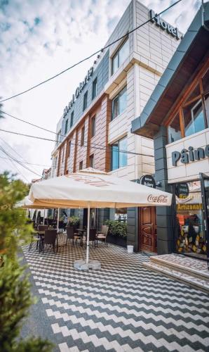 a patio with tables and umbrellas in front of a building at HOTEL GLARIS in Tîrgu Frumos
