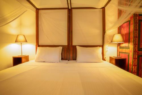 a bedroom with a large bed with two lamps at Villa Godahena in Ambalangoda