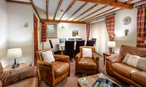 a living room with leather furniture and a table at Thomas Fold Cottage in Ambleside